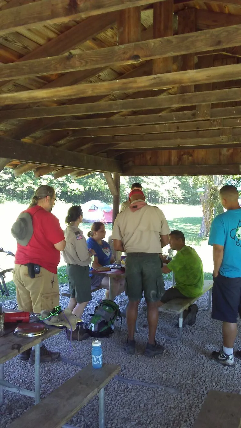 Adult Scout leader talking with a youth Scout at a camp site